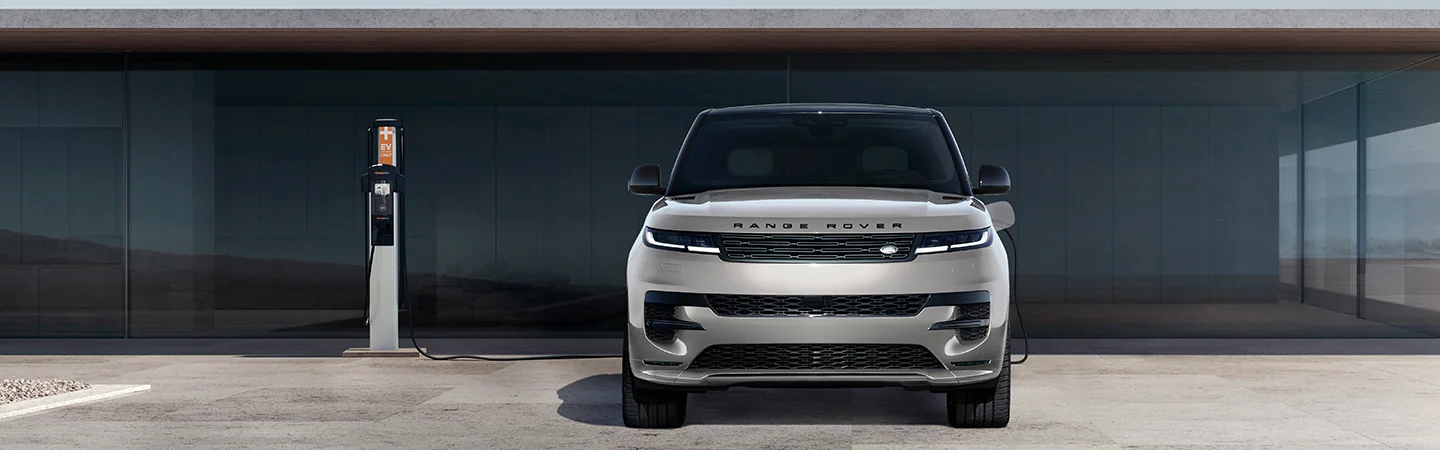 Front view of a parked 2025 Range Rover Hybrid charging in front of a house