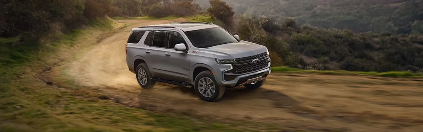 A gray 2024 Chevrolet Tahoe driving down a dirt road