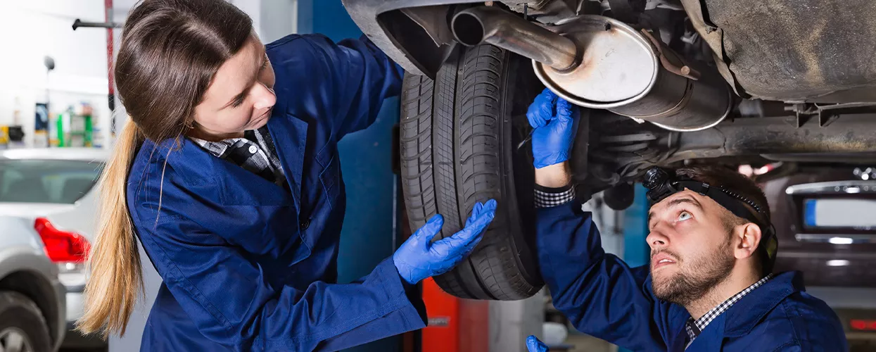 Two service mechanics working on a lifted vehicle