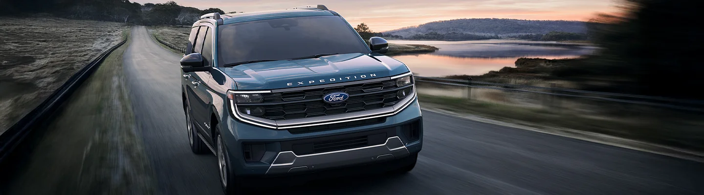 2025 Ford Expedition driving down a highway with a sunset in the background