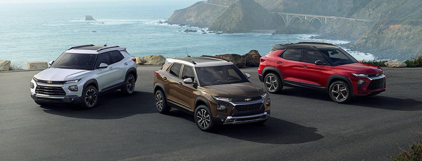 Three Chevy Trailblazers parked on an oceanside mountain road