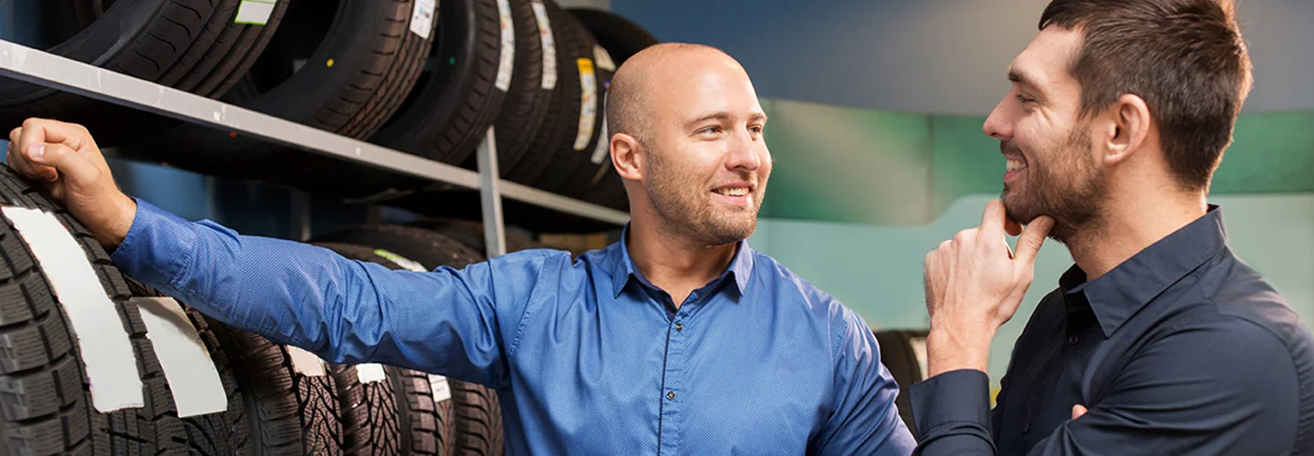 Two service techs talking over some tires