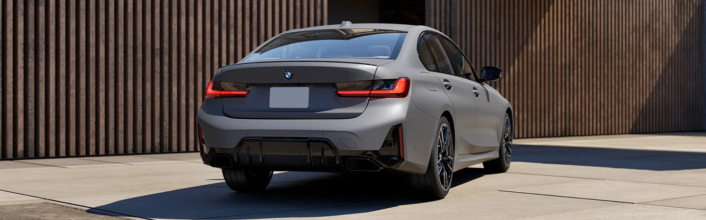 Back view of a parked gray 2025 BMW 330i in a driveway