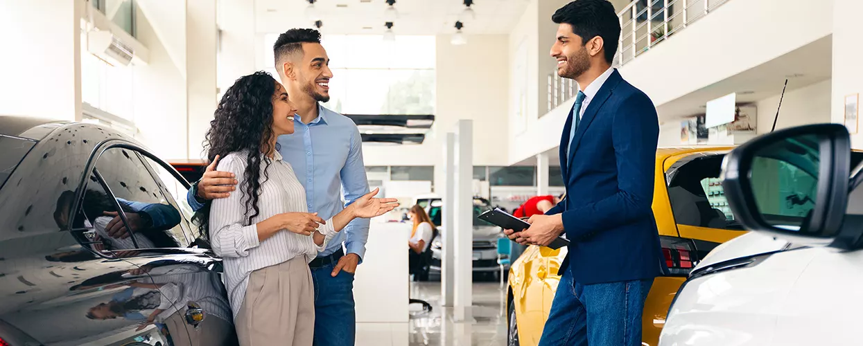 Car salesman talking to a couple at a dealership