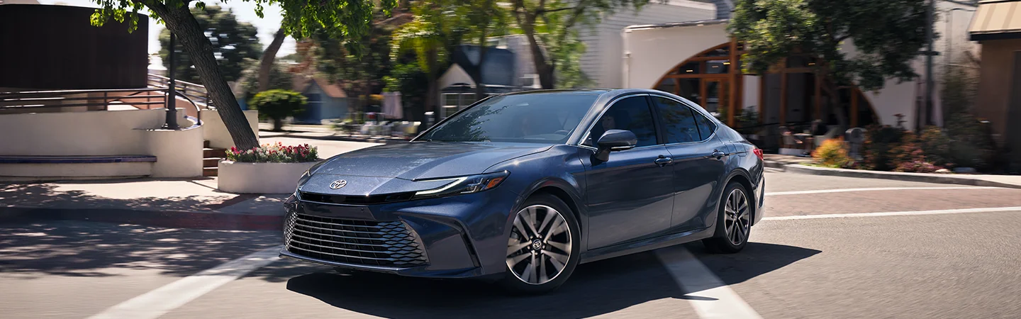 Side view of a blue 2026 Toyota Camry making a turn on a city street