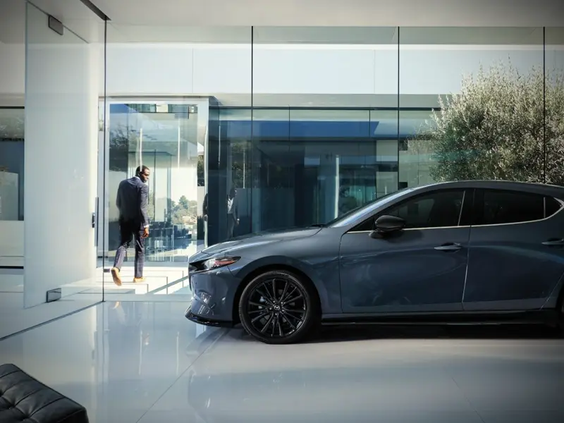 man parks new Mazda3 Hatchback in the showroom so he can get coffee