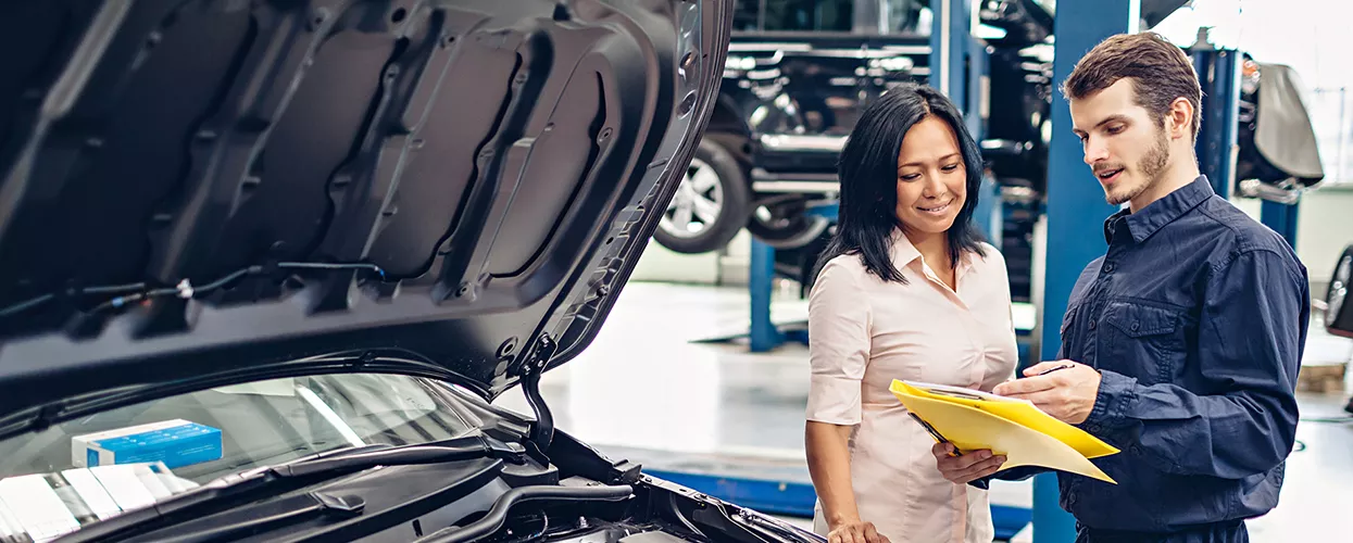 Service mechanic showing a car owner a paper on a clipboard