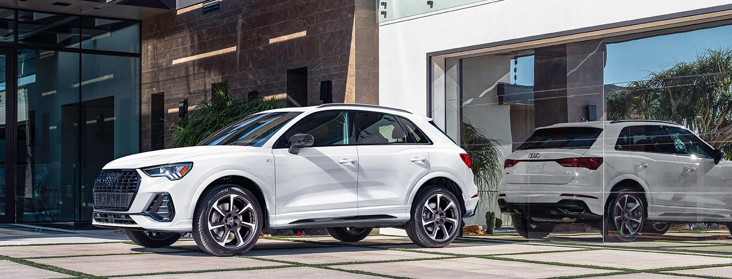 Side view of a white 2025 Audi Q3 parked by modern building