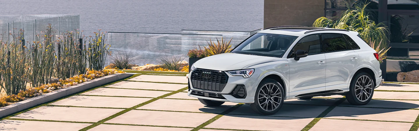 Front side view of a white 2025 Audi Q3 parked at a house with ascenic view