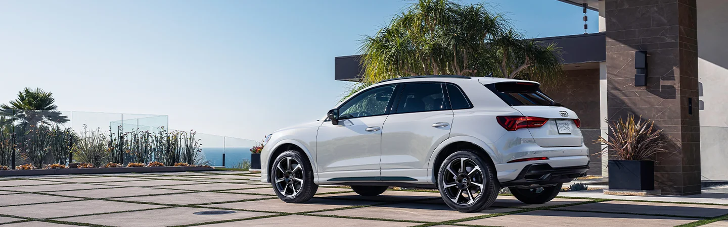 Rear view of a white 2025 Audi Q3 at a ocean side house