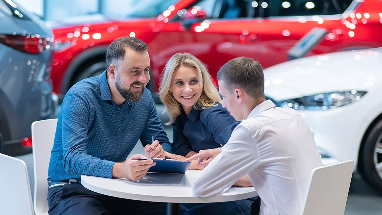 Three people sitting around a table at a car dealership