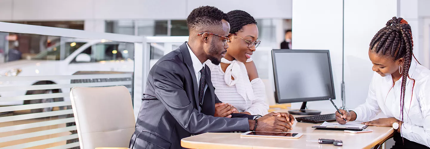 Three people sitting at a table discussing buying a new car