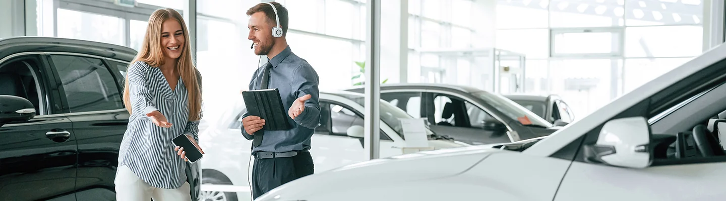 Salesman and woman pointing open handed at a car