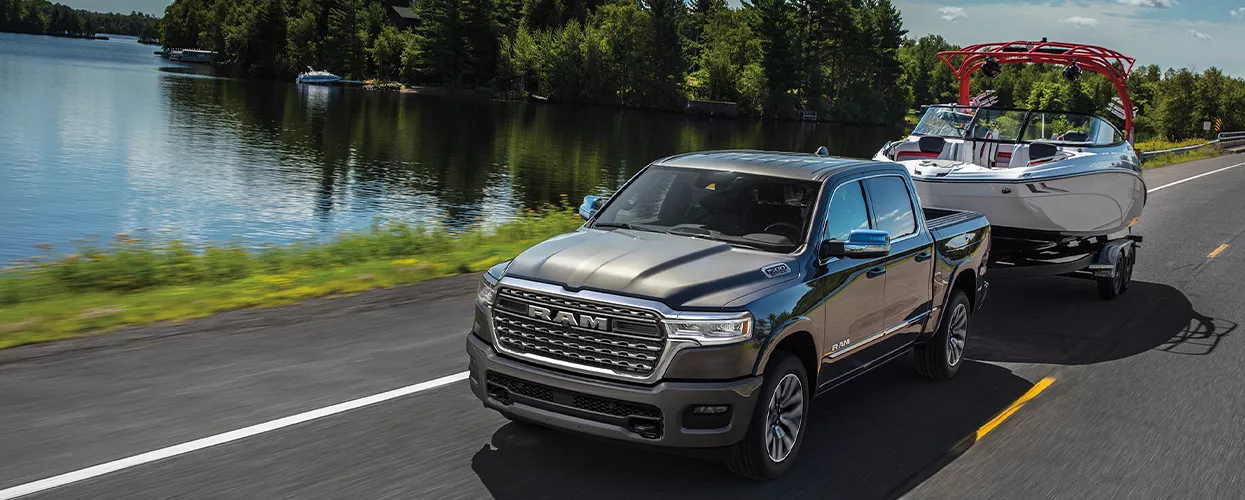 RAM Truck towing a small boat on a road next to a lake