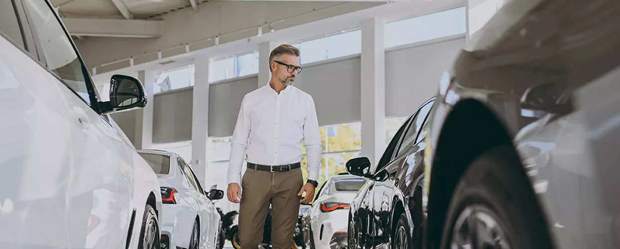 Someone walking through a dealership looking at new vehicles