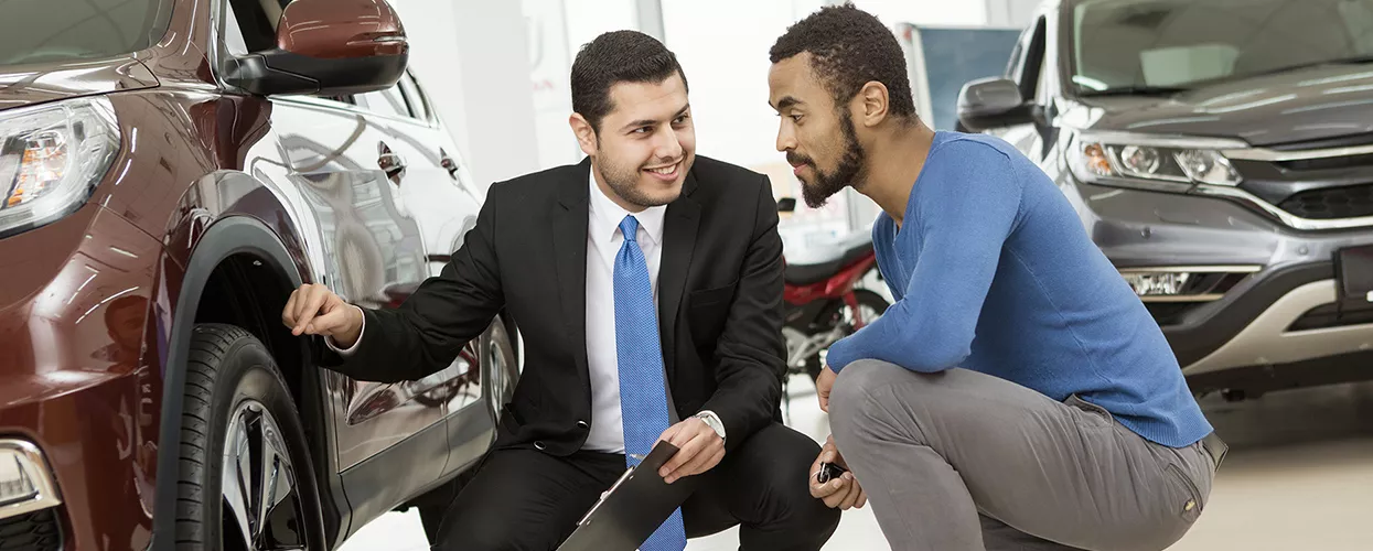 Car salesman showing a customer a car in a dealership