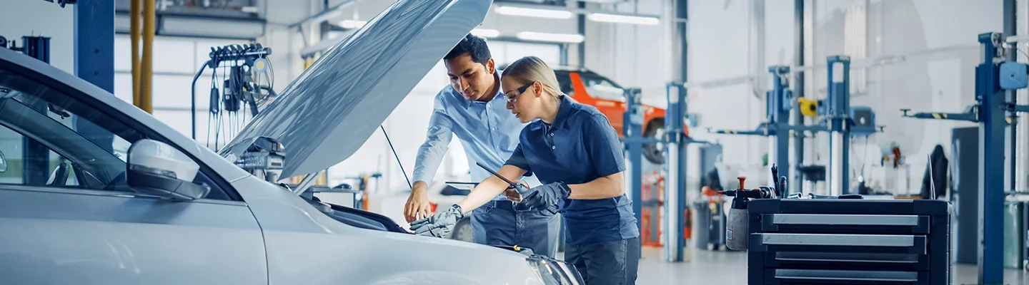 mechanic and tech working under the hood of a vehicle