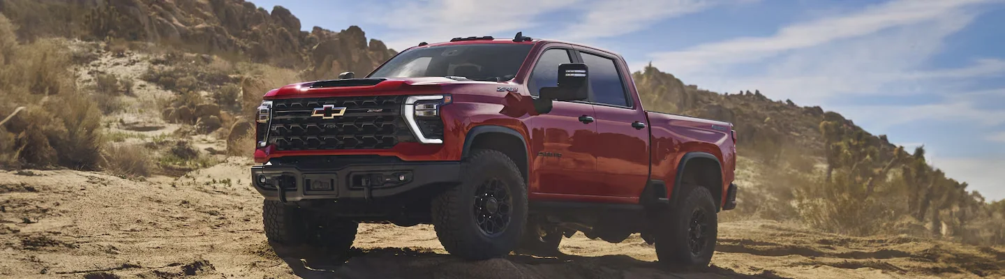 A red 2024 Chevy Silverado 2500 parked on a rocky cliff side