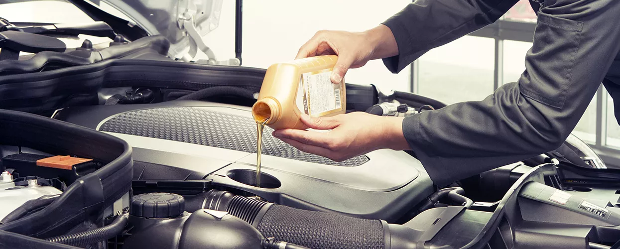Service mechanic pouring oil into a car