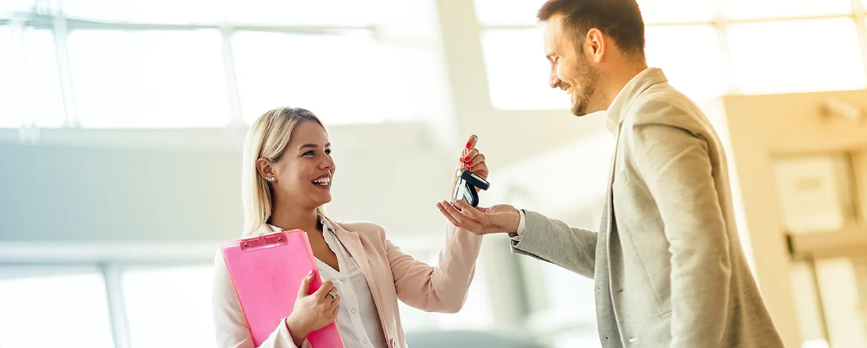 car salesperson handing over keys to a car to another person