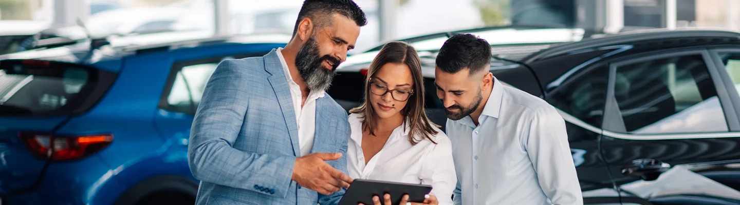 3 people looking at a pad with vehicle information it