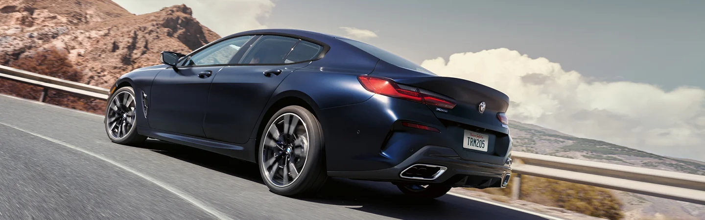 2025 BMW 8 Series dark blue color var driving on mountain with side view