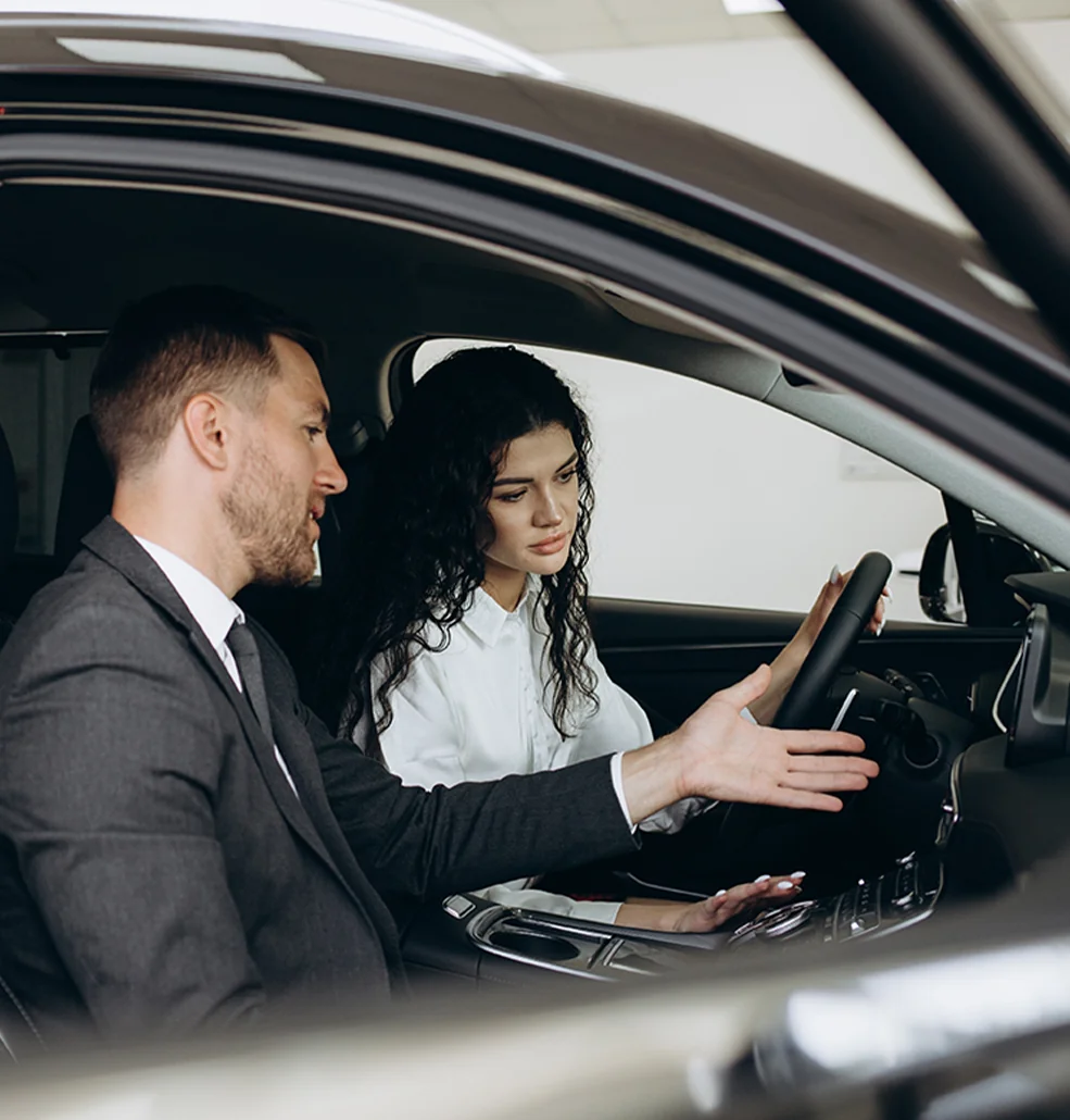 Customer and sales person sitting in a car talking about the features