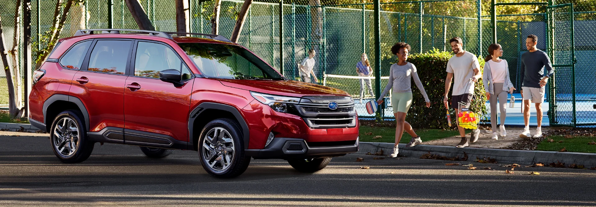 People just finished playing tennis walking to there red Subaru SUV