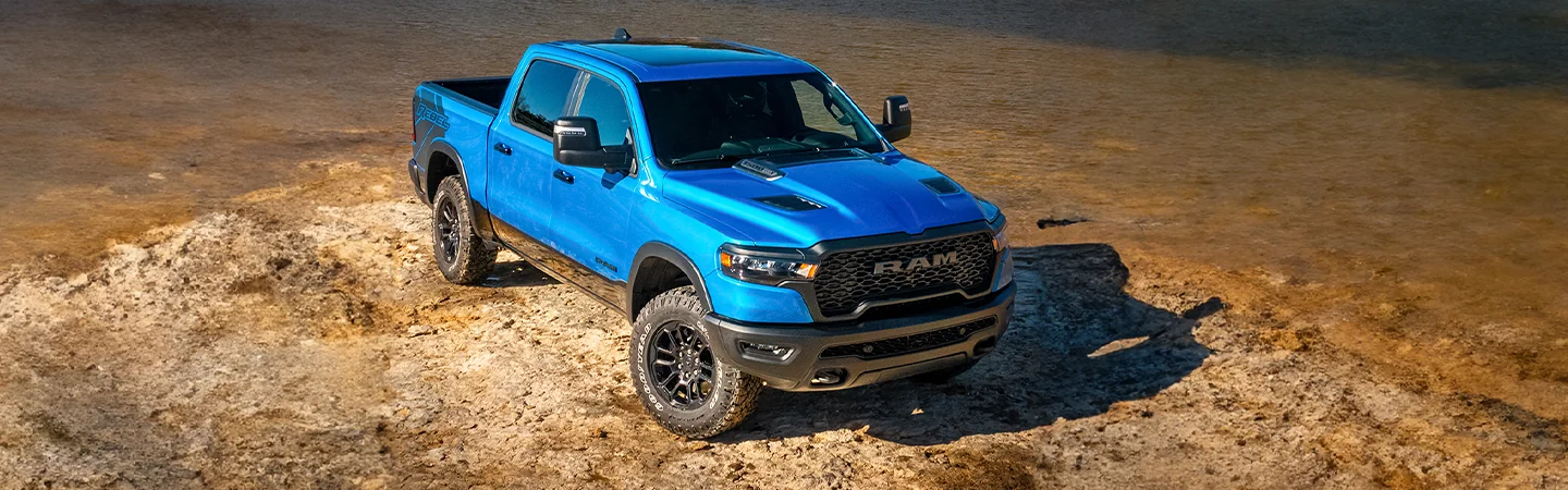 a blue 2026 RAM 1500 Tradesman parked by a river