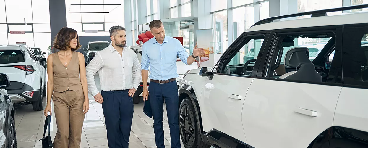 Car salesman showing a couple a new Land Rover vehicle