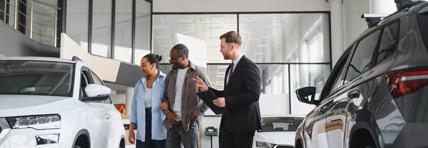 Car salesman showing a couple a new vehicle