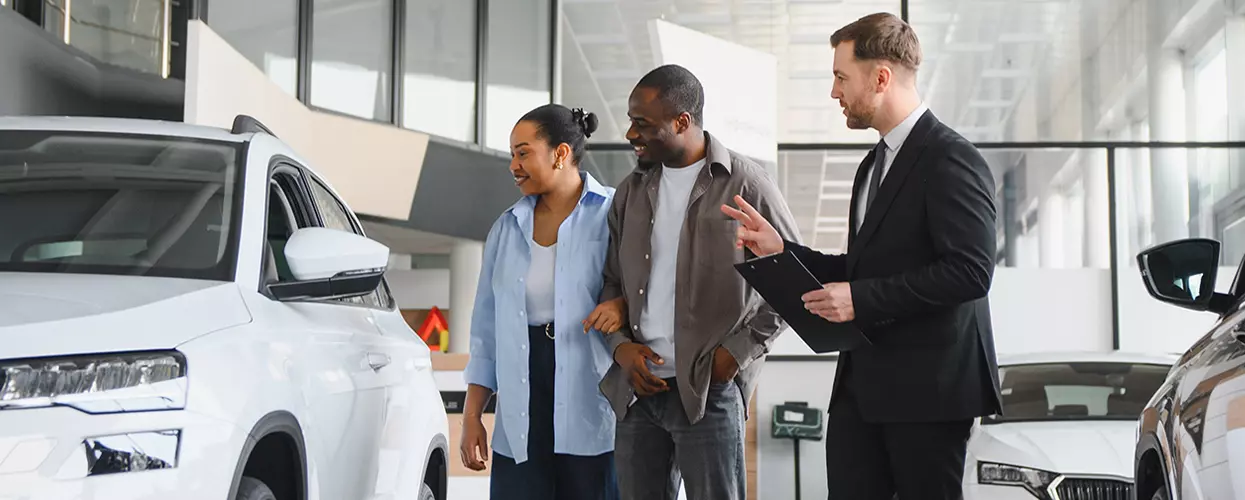 Car salesman showing a couple a new vehicle in a car dealership