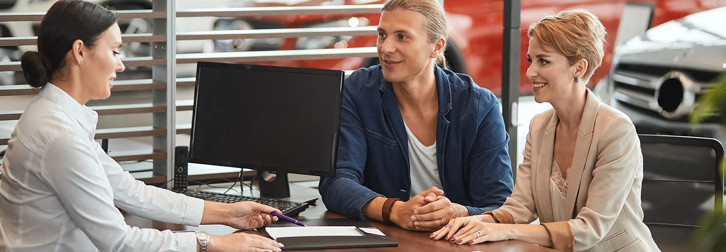 couple speaking with car salesperson in showroom