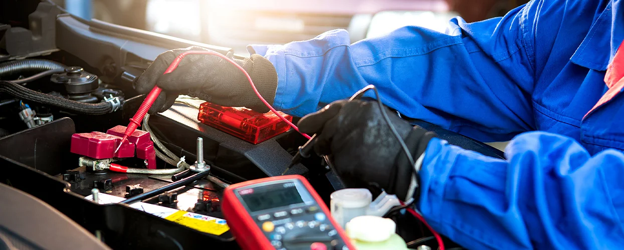 car mechanic testing voltage on engine