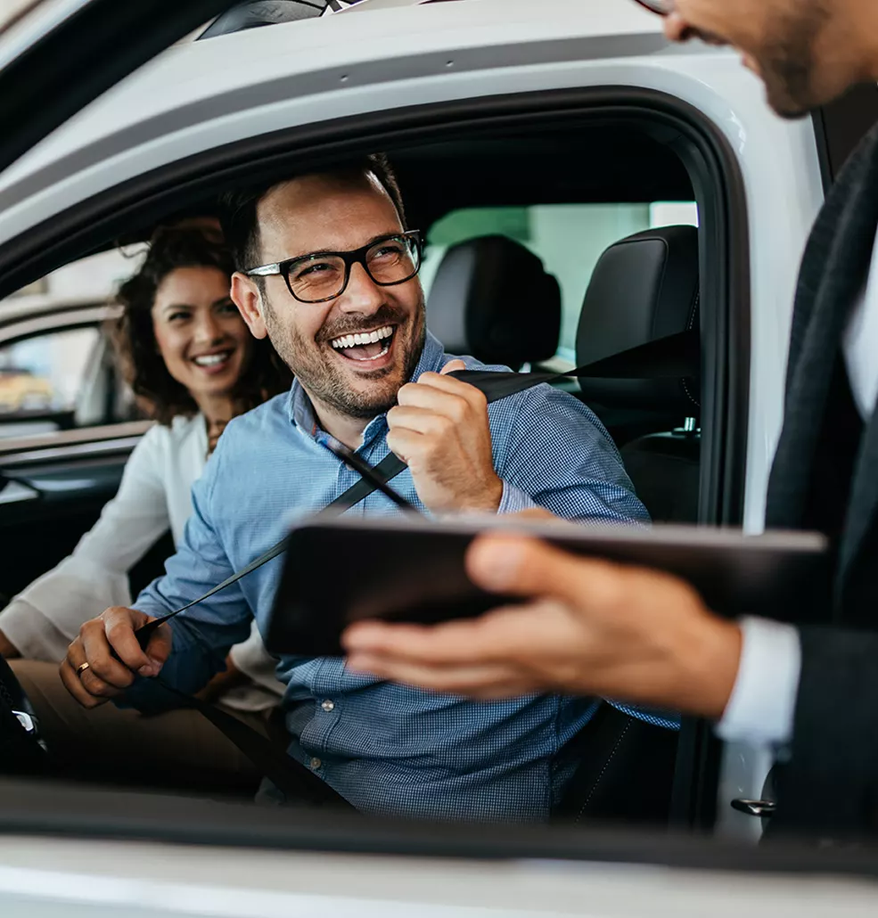 Couple sitting in a new car talking with a car salesman