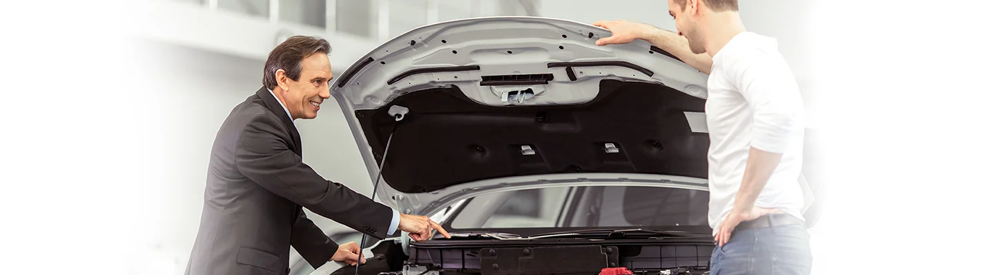 salesperson showing person trunk of new car