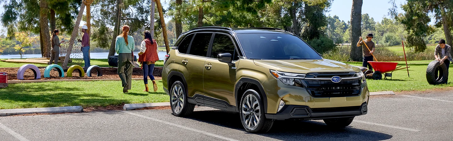 Front view of a parked gold 2025 Subaru Forester parked at a playground with people working on the park in South Chesterfield, VA.