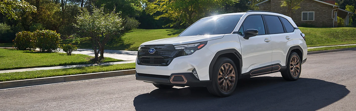 Front side view of a white 2025 Subaru Forester driving down a neighborhood street in South Chesterfield, VA.