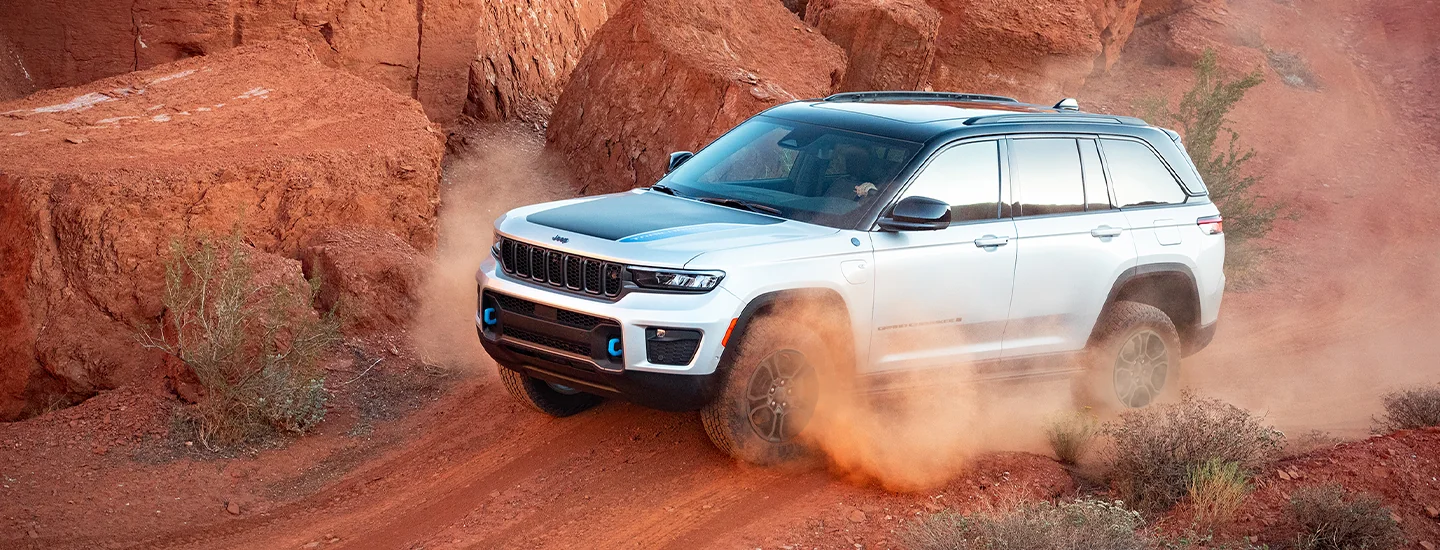 A white 2025 Jeep Grand Cherokee driving in dirt
