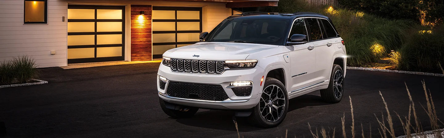 A white 2025 Jeep Grand Cherokee parked in a driveway
