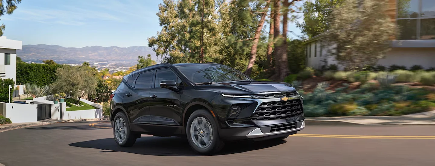 Black 2025 Chevrolet Blazer driving past some houses.