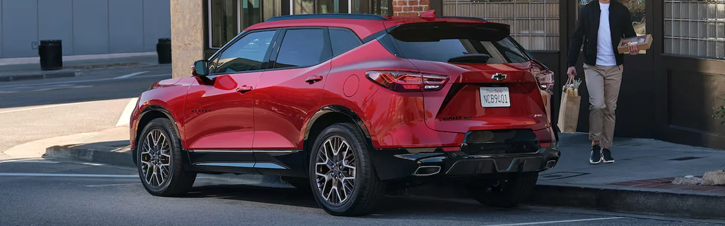 Back side view of a parked red 2025 Chevrolet Blazer 2LT on a city street