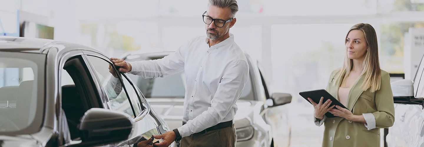 Sales person showing customer a new car