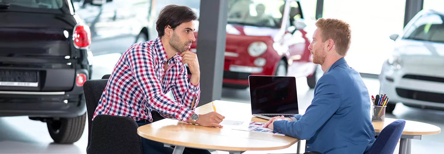 Car salesman talking to a customer in a car dealership