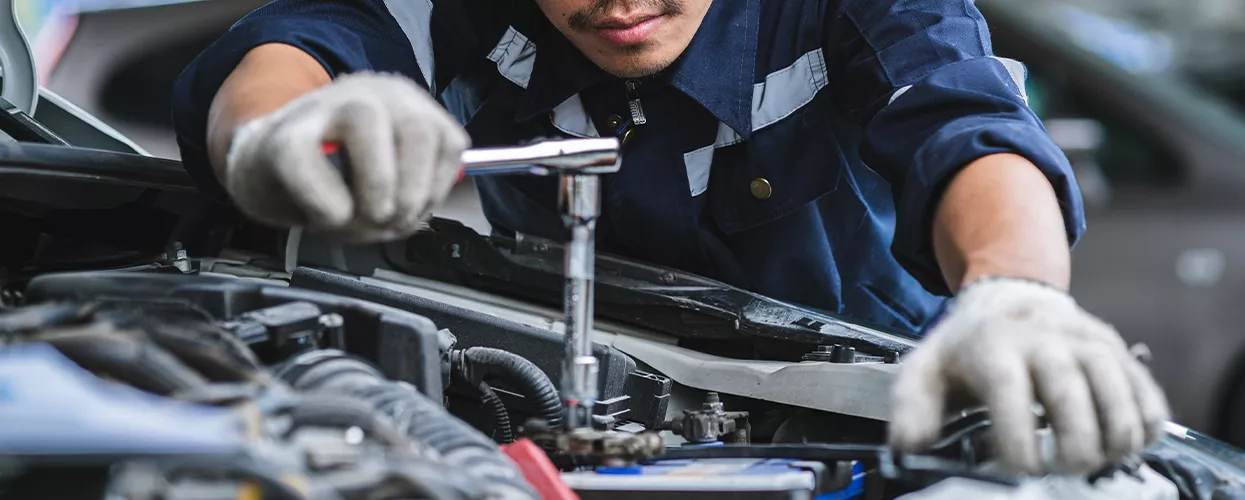 Service mechanic working under the hood of a vehicle