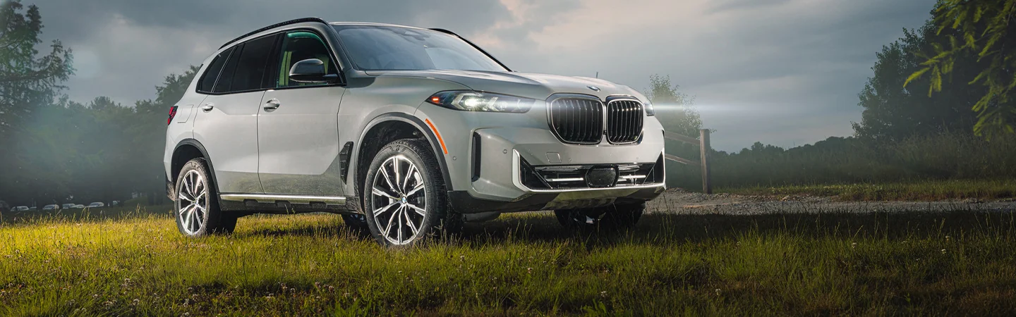 white front view of a 2025 BMW X5 sDrive40i parked at night with lights on