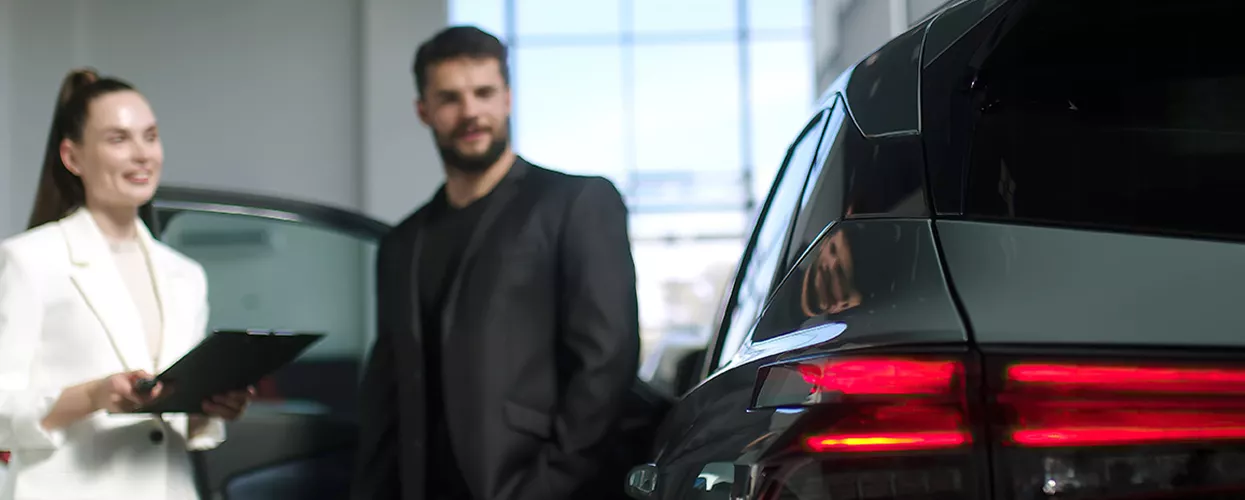 Car saleswoman and customer standing outside a vehicle