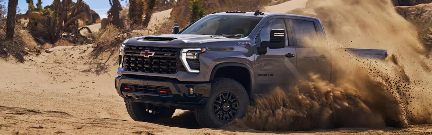 A gray 2025 Chevrolet Silverado HD driving around in the dirt