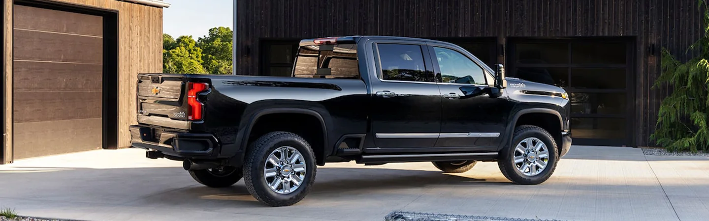 Side view of a black 2025 Chevrolet Silverado HD parked in the drive way