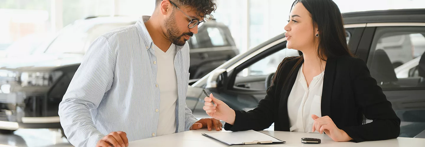 Car saleswoman talking to a customer about a contract at a car dealership